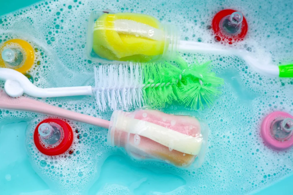 Mother cleaning baby bottles before sterilizing in a modern kitchen